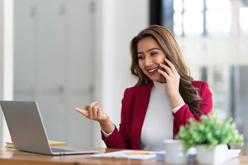 Smiling beautiful Asian businesswoman analyzing chart and graph showing changes on the market and...