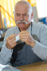 senior man with needle in mouth sewing