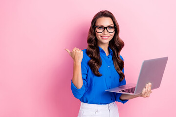 Photo of gorgeous smart woman with curly hairdo dressed blue blouse directing empty space hold laptop isolated on pink color background