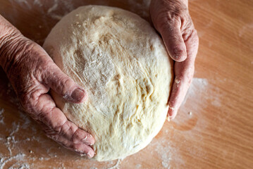 Grandmother's hands close-up prepare homemade dough. Top view.