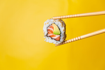 Salmon uramaki grabbed by wooden chopsticks