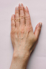 Female aging left hand with wrinkles, blood vessels and veins on an isolated background