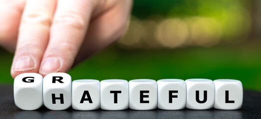 Hand turns dice and changes the word hateful to grateful.