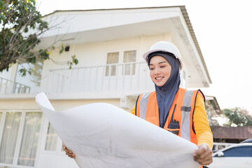 Asian female muslim engineer worker wear hijab headscarf working with home building blueprint outdoor