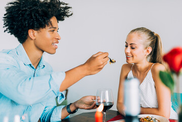 Happy young in love interracial couple having romantic dinner on