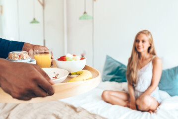 Obraz na płótnie Canvas Young beautiful interracial couple having a surprise breakfast in bed .