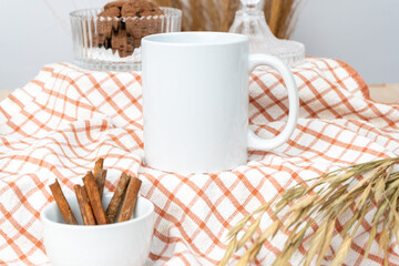 A white blank coffee mug on the top of a hand cloth arranged with some stuff around it