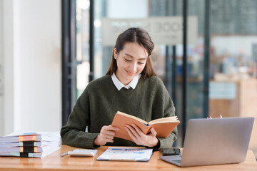 Beautiful Asian businesswoman working on her laptop and having fun at work and read with peace of mind.