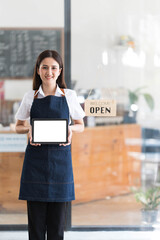 Fototapeta Young asia business owner woman with apron with open sign at cafe open again, showing blank white screen of tablet. obraz