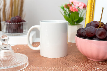 A white blank coffee mug on the top of a rounded mat decorated with simple stuff around it
