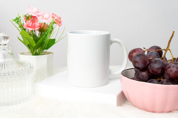 A white blank coffee mug on the top of a rounded mat decorated with simple stuff around it