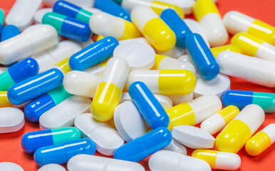 Colored pills, pills and capsules on a red background
