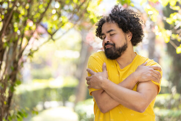 Naklejka na ściany i meble young Mexican man with beard and afro hugging himself, self love