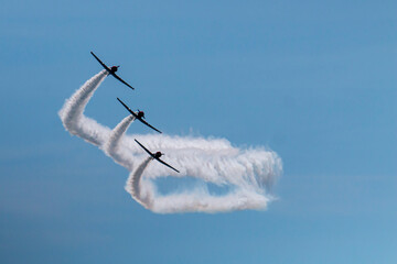 Three members of the Skytypers acrobatic airplane performance team perfoming at the Jones Beach Air Show leaving a long smoke trail - obrazy, fototapety, plakaty