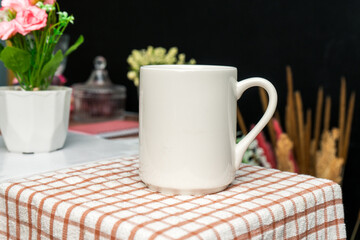 A white blank coffee mug on the top of a hand cloth with simple decorations arranged around it