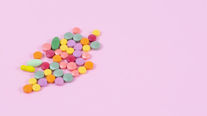 Macro shot of multi-colored pills and capsules heap on a pink background Medical