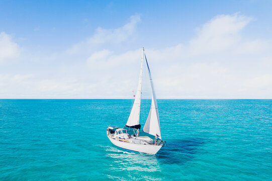 Sailboat Sailing Through Turquoise Bahamas Waters with Woman on Bow