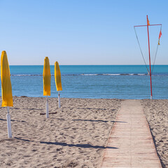 wooden path on the sandy beach leading to the sea against the blue sky