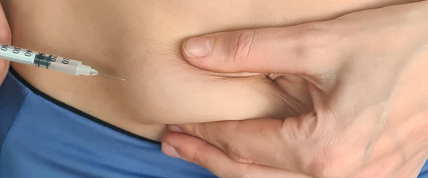 Closeup of woman giving injection in stomach