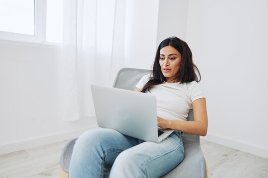 Woman relaxing at home sitting in a chair with her laptop and talking on video call with friends in covid-19, lifestyle home spirits. Mockup, free copy space