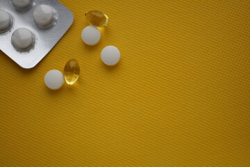 White pills on a yellow background. Blister with tablets. A place for writing. Background with medicines. Vitamins on a yellow background. Antibiotics