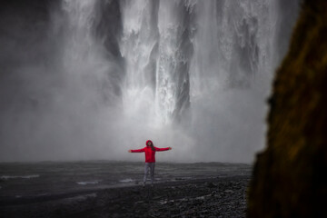 Fearless strong woman faces powerful waterfall; concept of strong and invincible woman, female...