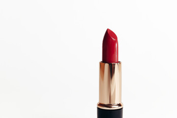 Isolated new red lipstick without cap in a golden container on a white background, macro photo