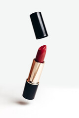 Red lipstick with opened cap, cosmetics, levitation, on white background