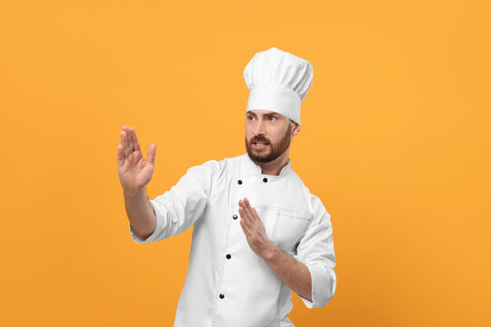 Emotional mature male chef on orange background