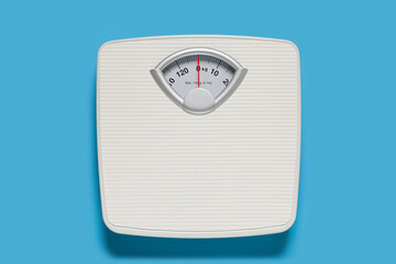 Bathroom scale on light blue background, top view