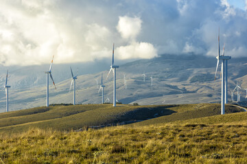 A wind farm or wind park at sunset located on the mountains of Italy Europe and it allows to...
