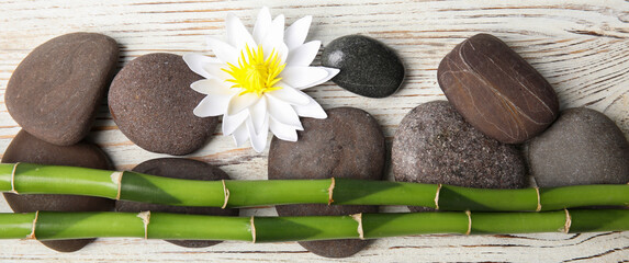 Spa treatment. Flat lay composition with stones, bamboo and lotus flower on white wooden table....