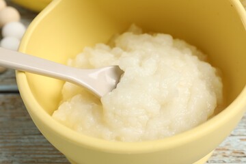 Baby food. Bowl with cauliflower puree on rustic wooden table, closeup