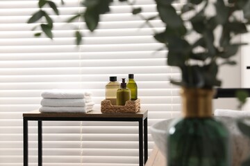 Soft towels and toiletries on wooden table in bathroom. Interior design