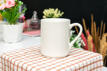 A white blank coffee mug on the top of a hand cloth with simple decorations arranged around it