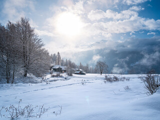 Winter in the italian Alps. Beautiful view of idyllic village in snowy forest and snowcapped mountain peaks. Piedmont, Italy.