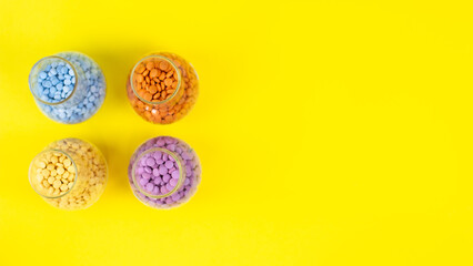 Colorful assorted pharmaceutical medicine pills, tablets and capsules and bottle on yellow background. Capsules Vitamin And Dietary Supplements Space for text on the right