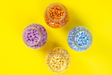 Colorful assorted pharmaceutical medicine pills, tablets and capsules and bottle on yellow background. Capsules Vitamin And Dietary Supplements Close up