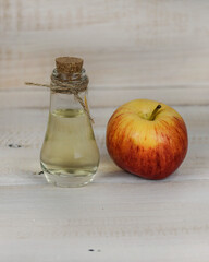Apple cider vinegar and fresh apple on a wooden background.