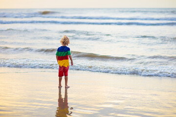 Child playing on ocean beach. Kid at sunset sea.