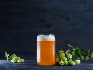 Hopped craft beer, india pale ale . Green hop cones, stylish glass can