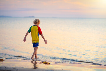 Child playing on ocean beach. Kid at sunset sea.