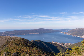 Panoramic view from mountain summit of Sveti Ilija on Kotor bay in sunny summer, Adriatic Mediterranean Sea, Montenegro, Balkans, Europe. Fjord winding along coastal town Tivat. Hiking in Dinaric Alps