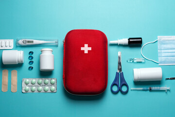 Home first aid kit on a blue background. The elements of the first aid kit are laid out on the...