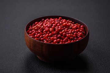 Spice, allspice peas of red or pink color in a wooden bowl