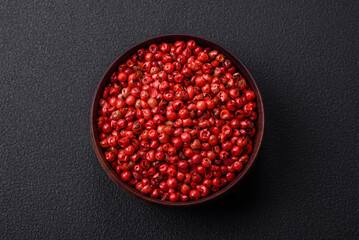 Spice, allspice peas of red or pink color in a wooden bowl