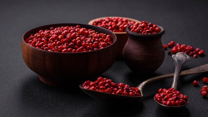 Spice, allspice peas of red or pink color in a wooden bowl