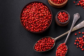Spice, allspice peas of red or pink color in a wooden bowl