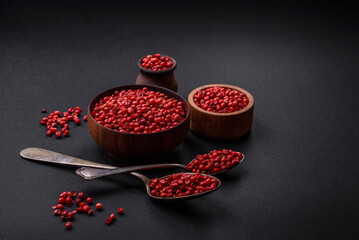 Spice, allspice peas of red or pink color in a wooden bowl