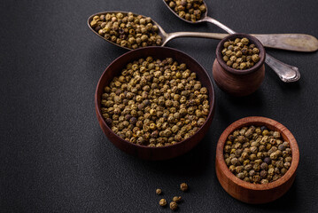 Spice, allspice green in a wooden bowl on a black concrete background